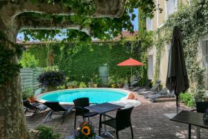 uma piscina com cadeiras e guarda-sóis ao lado de um edifício em CitHôtel Le Louvre em Orange