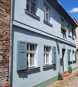 a blue house with white windows and a brick building at Ferienwohnung Kommunikation 5 in Brandenburg an der Havel