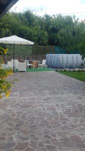 un patio con ombrellone, tavoli e sedie di B&B Villa dei Sogni a Eboli