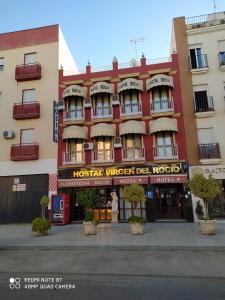 un edificio rojo con un hotel en una calle en Hostal Virgen Del Rocio, en Los Palacios y Villafranca