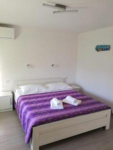 Una cama con una manta púrpura y dos zapatos blancos. en Apartman Studio Lu en Nerezine