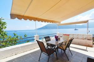 Ein Tisch und Stühle auf einem Balkon mit Blick auf das Meer in der Unterkunft Efi's Cottage by the sea in Fiskardo