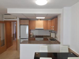 Una cocina con gabinetes de madera y un refrigerador blanco. en Piso centrico cerca del puerto, en Sant Carles de la Ràpita