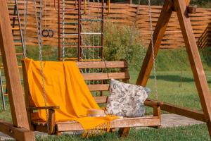 a wooden swing with an orange blanket and a pillow at Guest House Usadba in Stenino