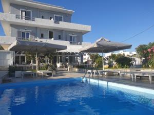 a hotel with a swimming pool with umbrellas at Syros Holidays in Vári