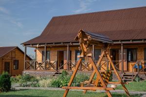 a wooden play structure in front of a house at Guest House Usadba in Stenino