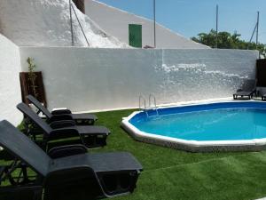 um pátio com cadeiras e uma piscina com relva em Casa Cueva Sol em Pozo Alcón