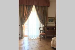 a room with a window with a chair and a desk at VelaLatina Residence B&B Soverato in Soverato Marina