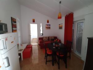 Apartment Enis في بارباريغا: مطبخ وغرفة معيشة مع طاولة وأريكة حمراء