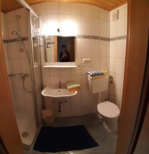Ein Mann fotografiert ein Bad mit WC und Waschbecken in der Unterkunft Ferienwohnung Schönauer in Haus im Ennstal