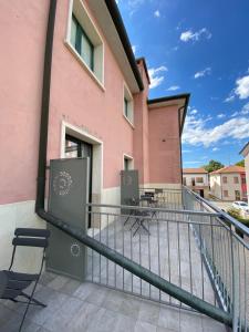Ein Balkon eines rosafarbenen Gebäudes mit Stühlen und Tischen in der Unterkunft Delta Park in Porto Viro