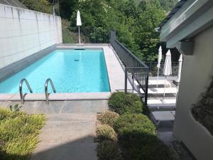 a large swimming pool with a staircase and a house at Casa di campagna Rosina con piscina e vista lago in Gravedona