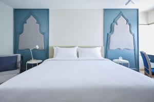 a bedroom with a white bed and blue walls at 56 Surawong Hotel Bangkok in Bangkok