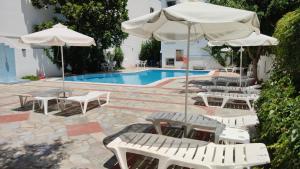 a group of white chairs and umbrellas next to a pool at Thalia deco City & Beach Hotel in Hersonissos