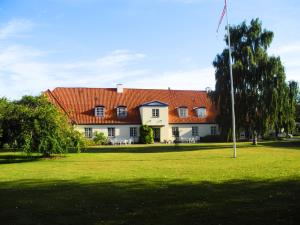 een groot wit huis met een oranje dak bij Inspiration Center Denmark, Guesthouse in Maribo