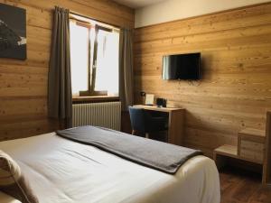 sypialnia z łóżkiem, biurkiem i telewizorem w obiekcie Hotel Nevada w mieście Bormio