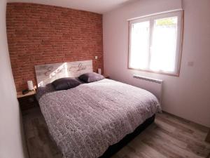 1 dormitorio con pared de ladrillo y 1 cama con 2 almohadas en Les Nuits Bonneuilloises Le Mustang, en Bonneuil-les-Eaux