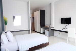 a bedroom with two beds and a desk and a television at De Vine House in Roi Et