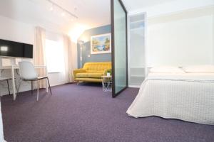 Habitación de hotel con cama y sofá amarillo en Miró Studio Apartments Dubrovnik, en Dubrovnik