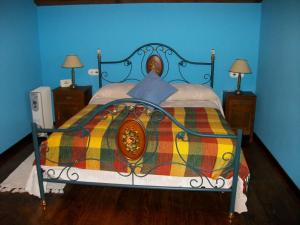 a blue bedroom with a bed with a colorful blanket at Casa de Aldea Rural Los Glayus in Luarca