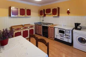 Una cocina con electrodomésticos rojos y blancos y una mesa. en Apartman Gržin, en Mošćenička Draga
