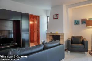 sala de estar con sofá de cuero negro y silla en Akivillas Quarteira Relax, en Quarteira