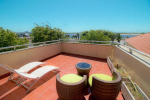 a balcony with chairs and tables on a roof at RIVERZENHOUSE in Esposende