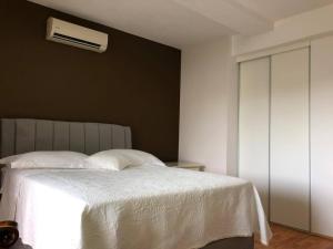 a bedroom with a white bed and a air conditioner at Nera Apartment in Brodarica