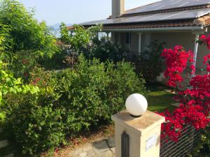 a garden with red flowers and a white ball on a post at Corinthian Sun - Vacation Home in Korinthos