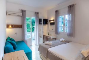 a bedroom with a bed and a couch and windows at Nefeli Hotel in Agios Nikitas