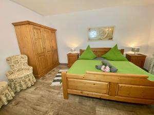 ein Schlafzimmer mit einem grünen Bett und einem Stuhl in der Unterkunft FeWo Rehblick in Schönau am Königssee