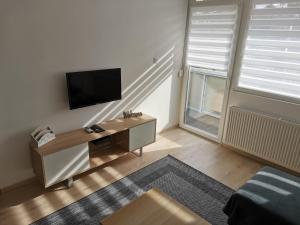 a living room with a desk with a television and a window at Sweet Life Apartman in Eger