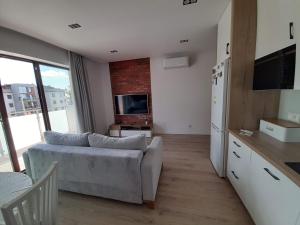 a living room with a couch and a tv and a refrigerator at Apartament LUX in Ełk