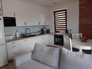 a kitchen with white cabinets and a table and a couch at Apartament LUX in Ełk