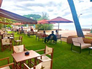 a group of people sitting in chairs under umbrellas near the beach at Rigat Park & Spa Hotel - Adults Recommended in Lloret de Mar