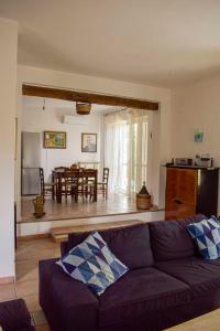 Affittacamere D'amore في Foria: غرفة معيشة مع أريكة أرجوانية وغرفة طعام