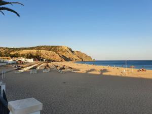 a sandy beach with chairs and people on the beach at Praia da Luz Monique Apartment in Luz