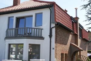 a house with a balcony and a brick building at Belle Villa in De Panne