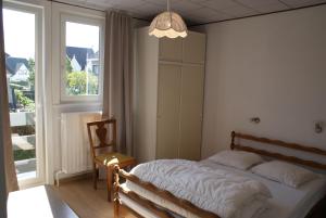 a bedroom with a bed and a chair and a window at Belle Villa in De Panne