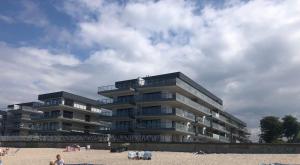 a large apartment building on the beach with people on the beach at Apartamenty Morskie Gardenia 2 in Dziwnów