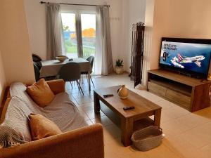 Helios Apartments - Beach of Lachania Rhodes في لاخنيا: غرفة معيشة مع أريكة وتلفزيون بشاشة مسطحة