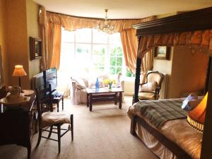 een slaapkamer met een bed, een tafel en een raam bij Glyn Isa Country House B&B and self catering Lodge in Conwy