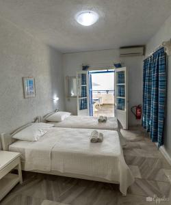two beds in a bedroom with a view of the ocean at Lina studios in Kalymnos