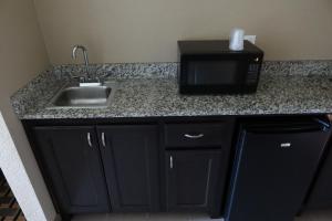 a kitchen counter with a microwave and a sink at West Worth Inn & Suites White Settlement in White Settlement +22 photos
