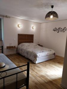een slaapkamer met een groot bed en een kroonluchter bij La Ferme Les Mamours in La Bastide-lʼÉvêque
