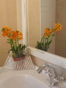 a bathroom sink with a vase with orange flowers in it at Via d'acqua Al Mulino -City Center- BO in Bologna