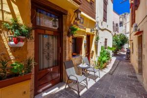 an alley with two chairs and a table in front of a building at Hamam Suites Portou in Chania Town