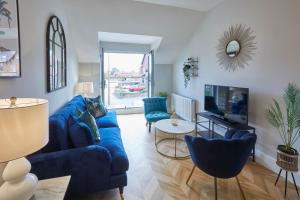 a living room with a blue couch and a tv at Host & Stay - Prospect Hill Apartments in Whitby