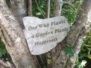 una señal de piedra que dice que uno que planta un jardín planta felicidad en The Garden Flat, en Crieff