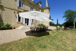 a table and chairs with an umbrella in front of a building at Château du Grava in Haux